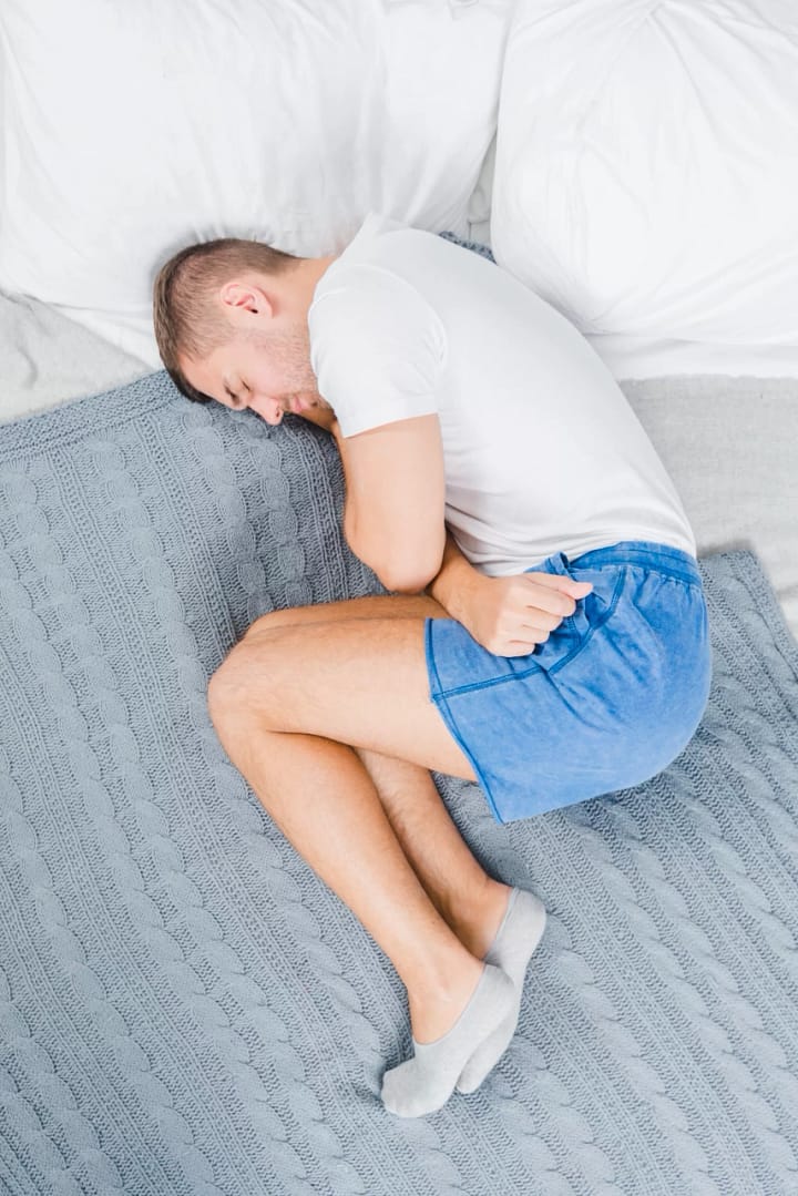 man suffering from stomach ache sleeping bed